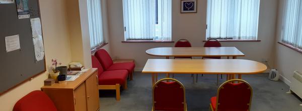 A room with two tables and chairs and some sofa chairs.