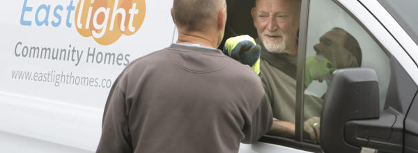 A man sat in an Eastlight van is talking through the window to a man standing next to the van.