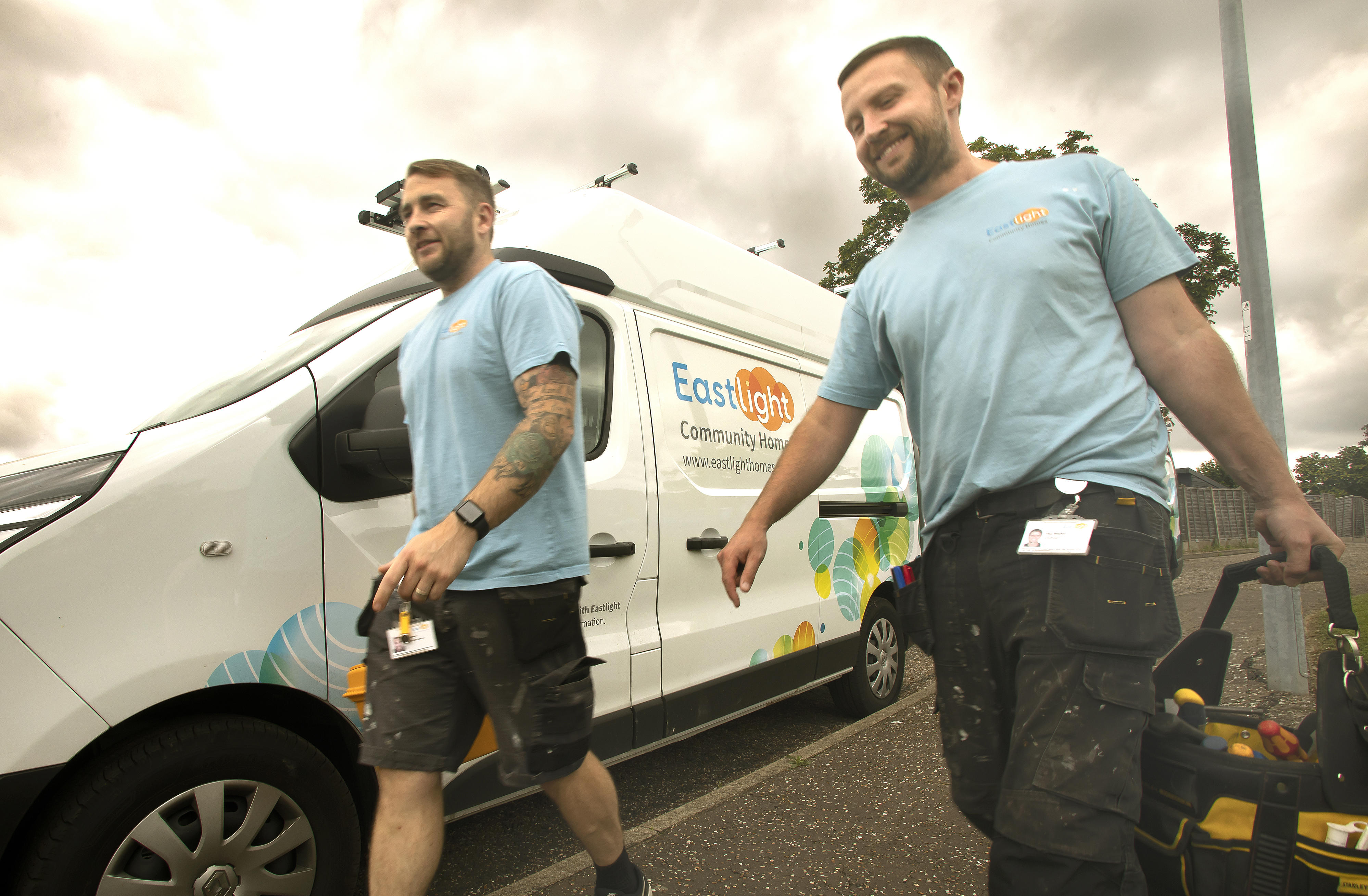 Two Eastlight tradesmen wearing Eastlight tshirts are walking beside an Easlight white van.