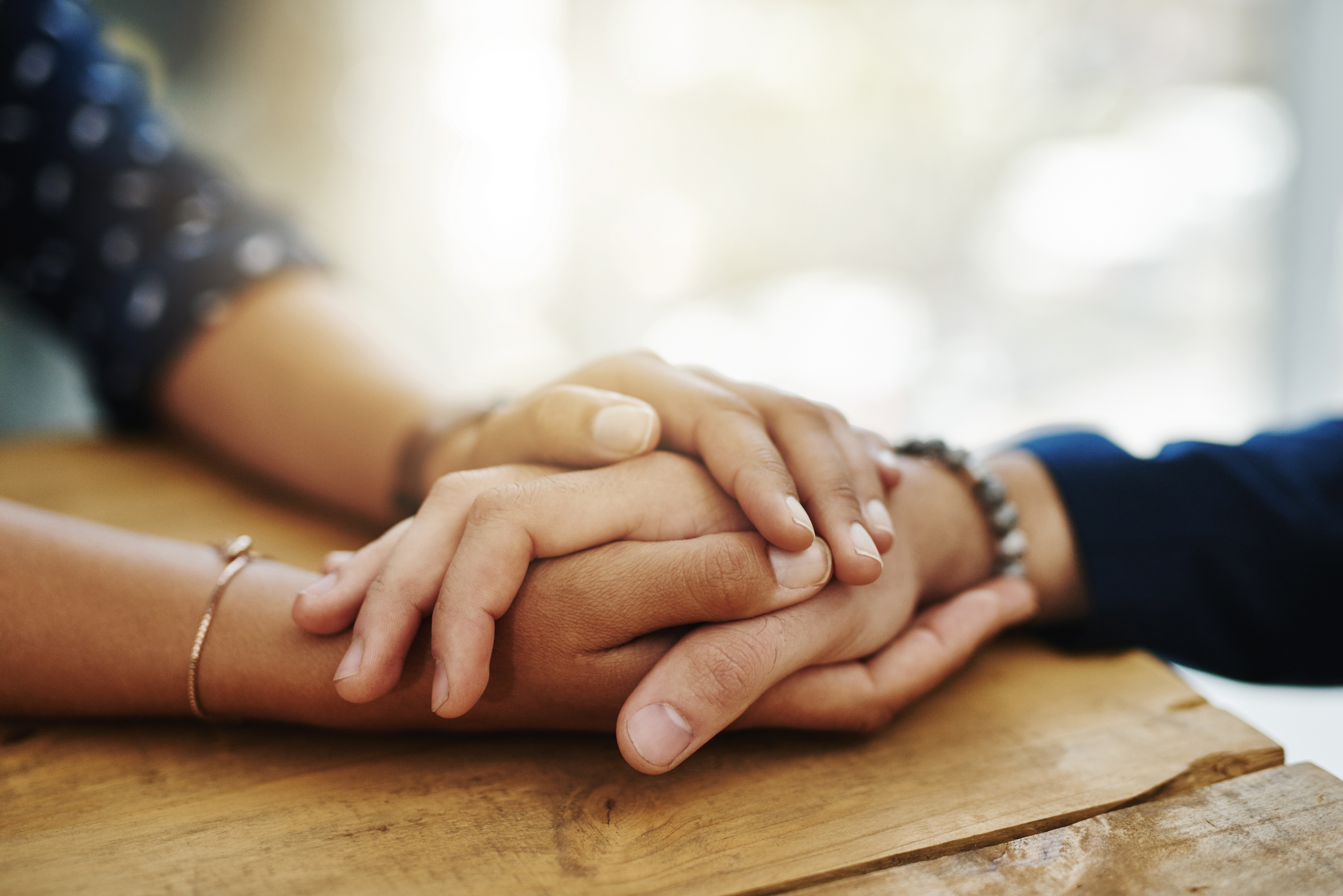 Two sets of hands clasped together as one.