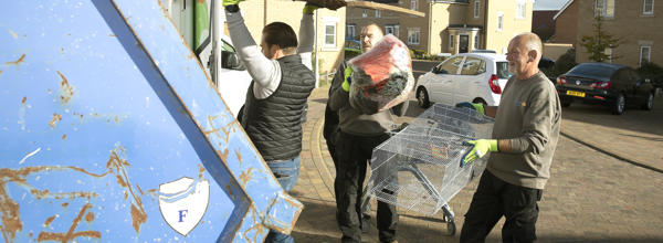 Three men from Eastlight are putting unwanted items into a skip.