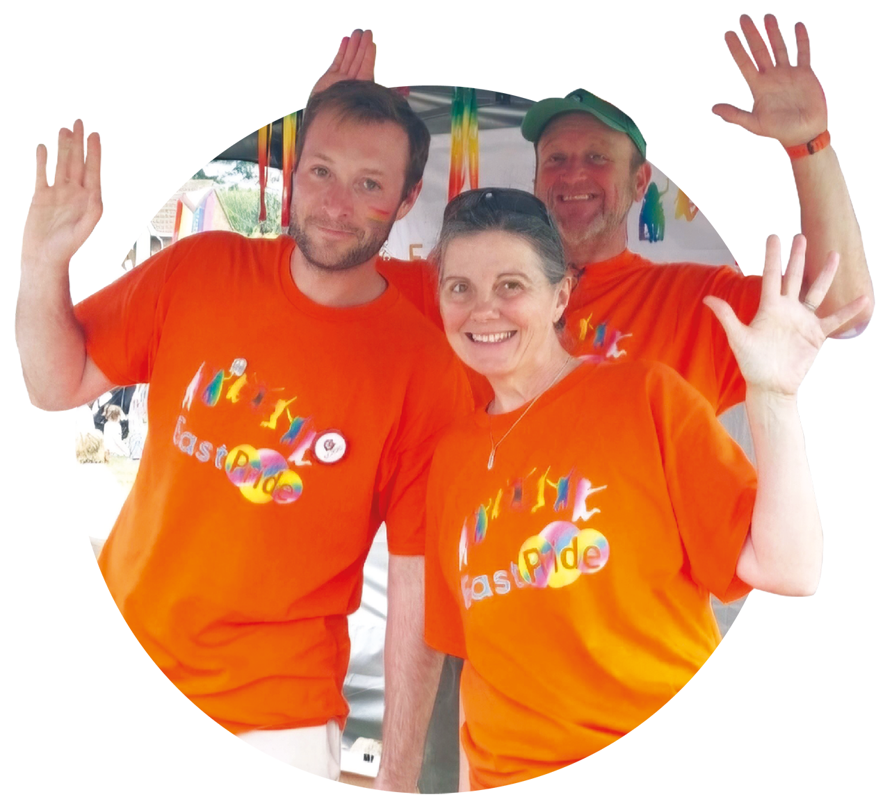 Two men and a woman are wearing orange t-shirts which say 'EastPride'. They are all waving at the camera.