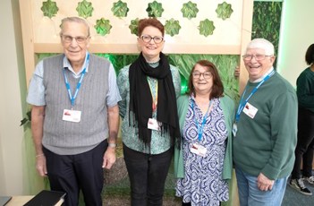 Two women stood in between two men. They are all smiling at the camera